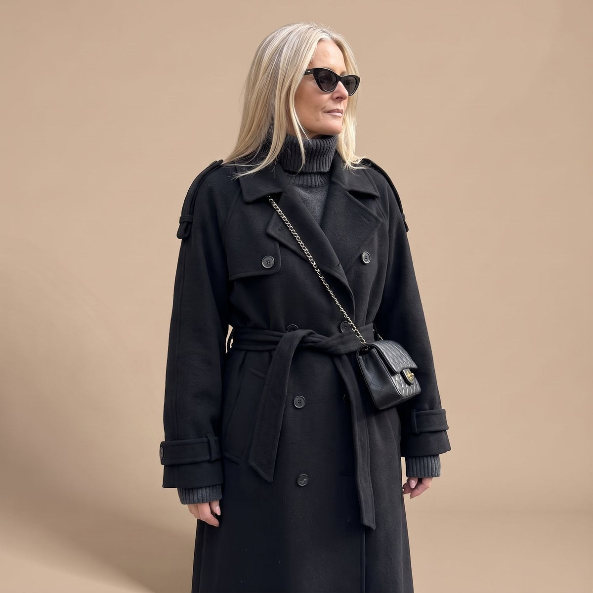 Zwarte trenchcoat gestyled over jeans voor een casual look