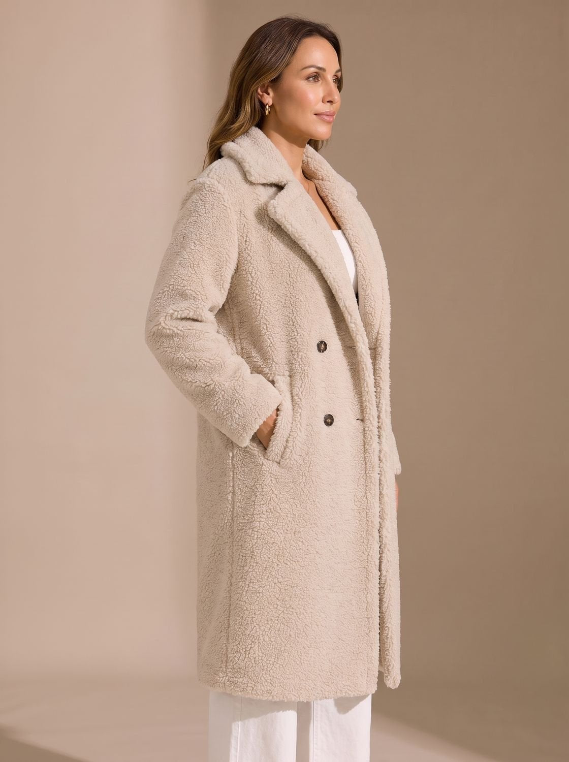 Close-up van het zachte teddy-fleece materiaal van de beige mantel