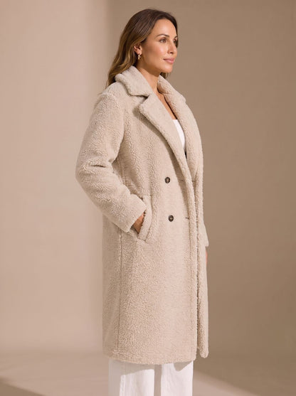 Close-up van het zachte teddy-fleece materiaal van de beige mantel